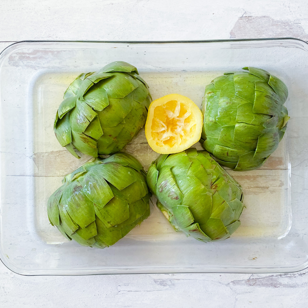 artichoke halves with a squeeze of lemon in baking dish